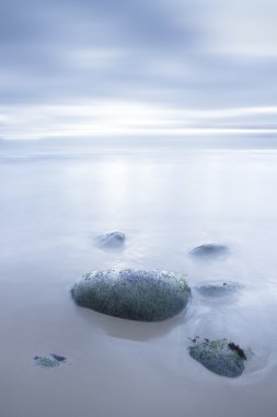 Water rocks and sand beach at sunset